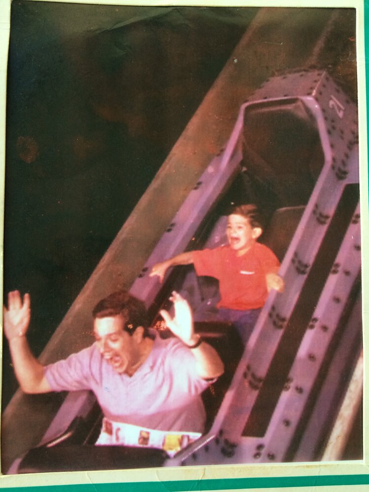 A young Alex Marcus riding a roller coaster with his father