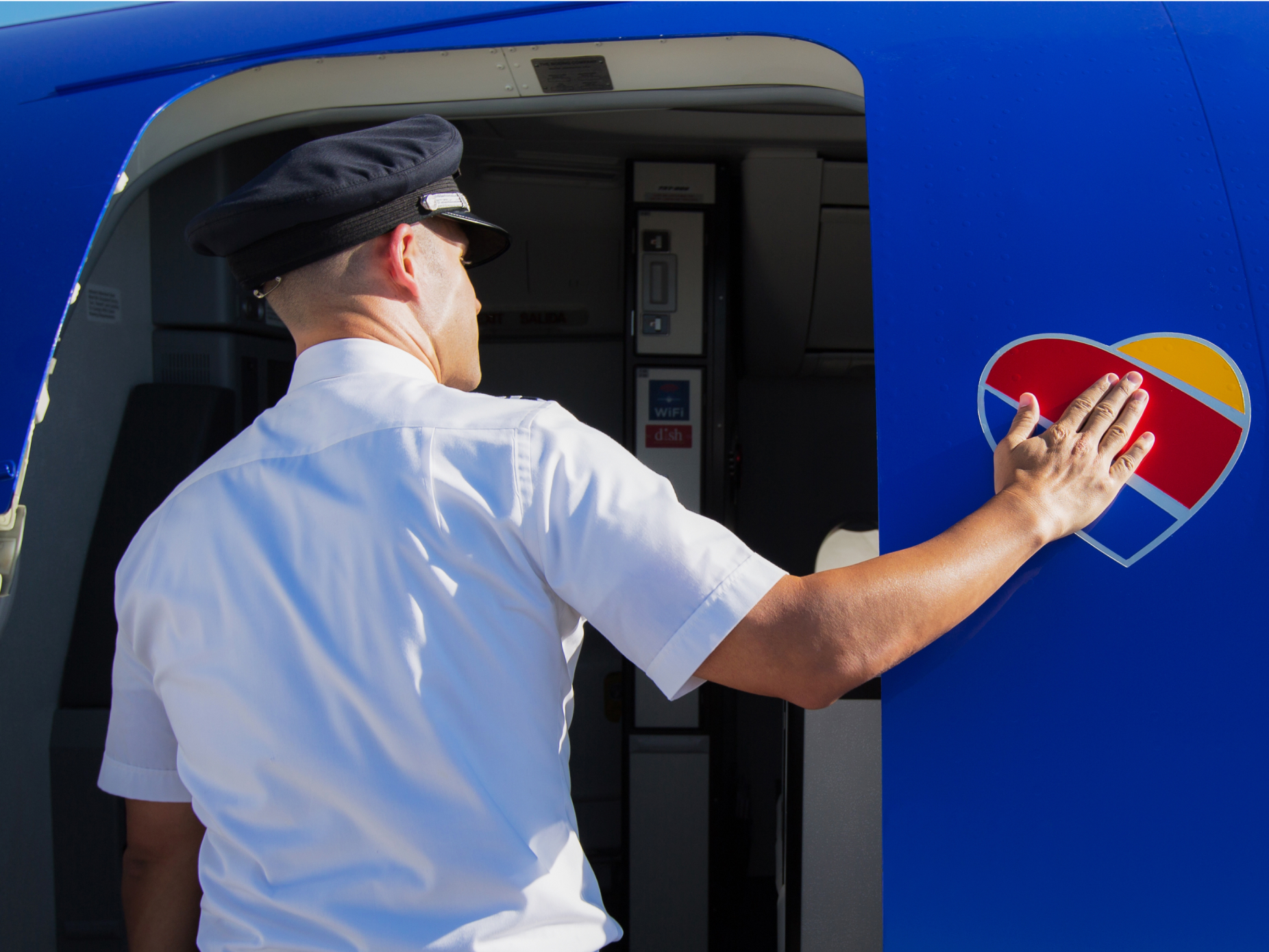 A Southwest Airlines pilot placing a hand on the redesigned heart on the plane's fuselage